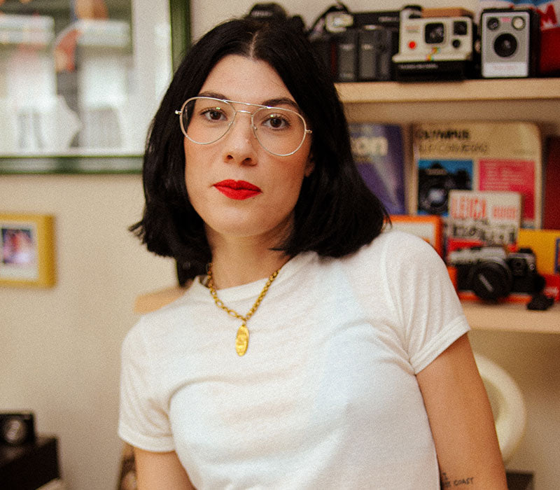 Photographer Lucy Lumen at home in front of cameras