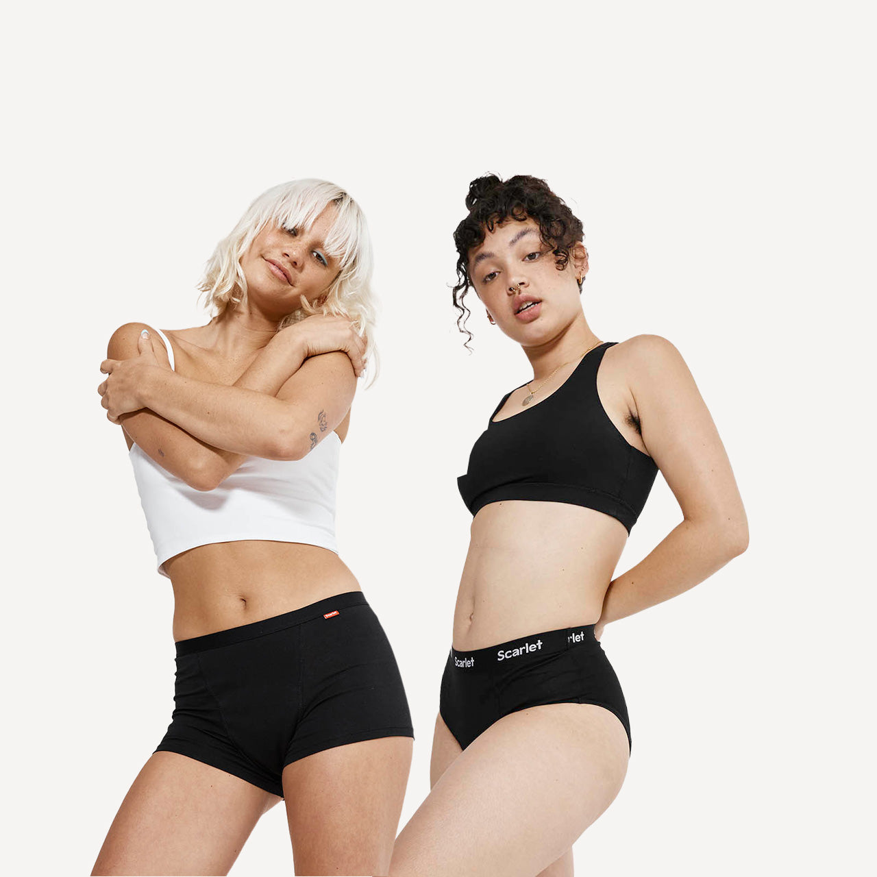 Two women wearing black underwear with visible branding on a white background