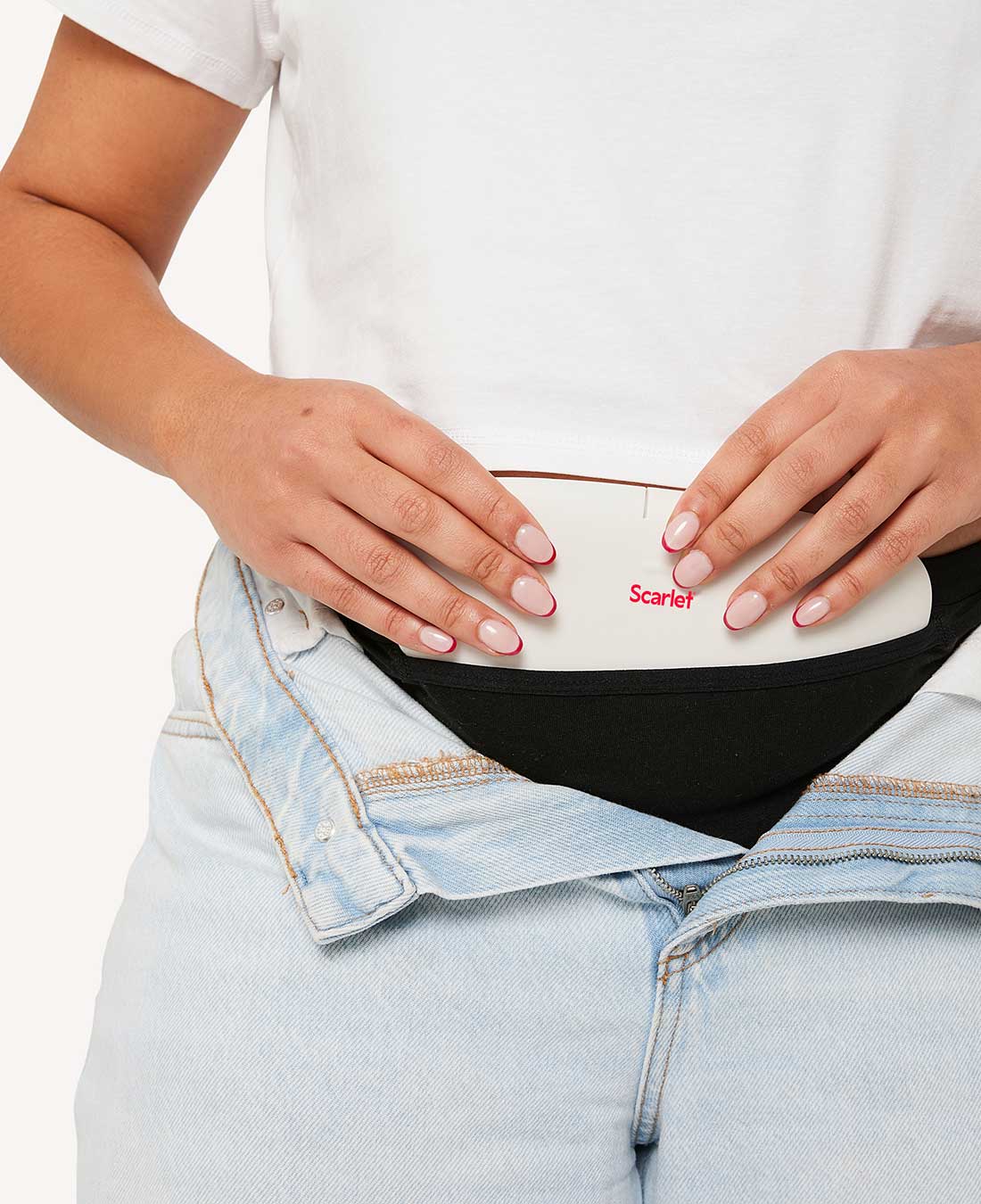 Hands settling the white rae heat pad into a black Scarlet pocket brief under open jeans