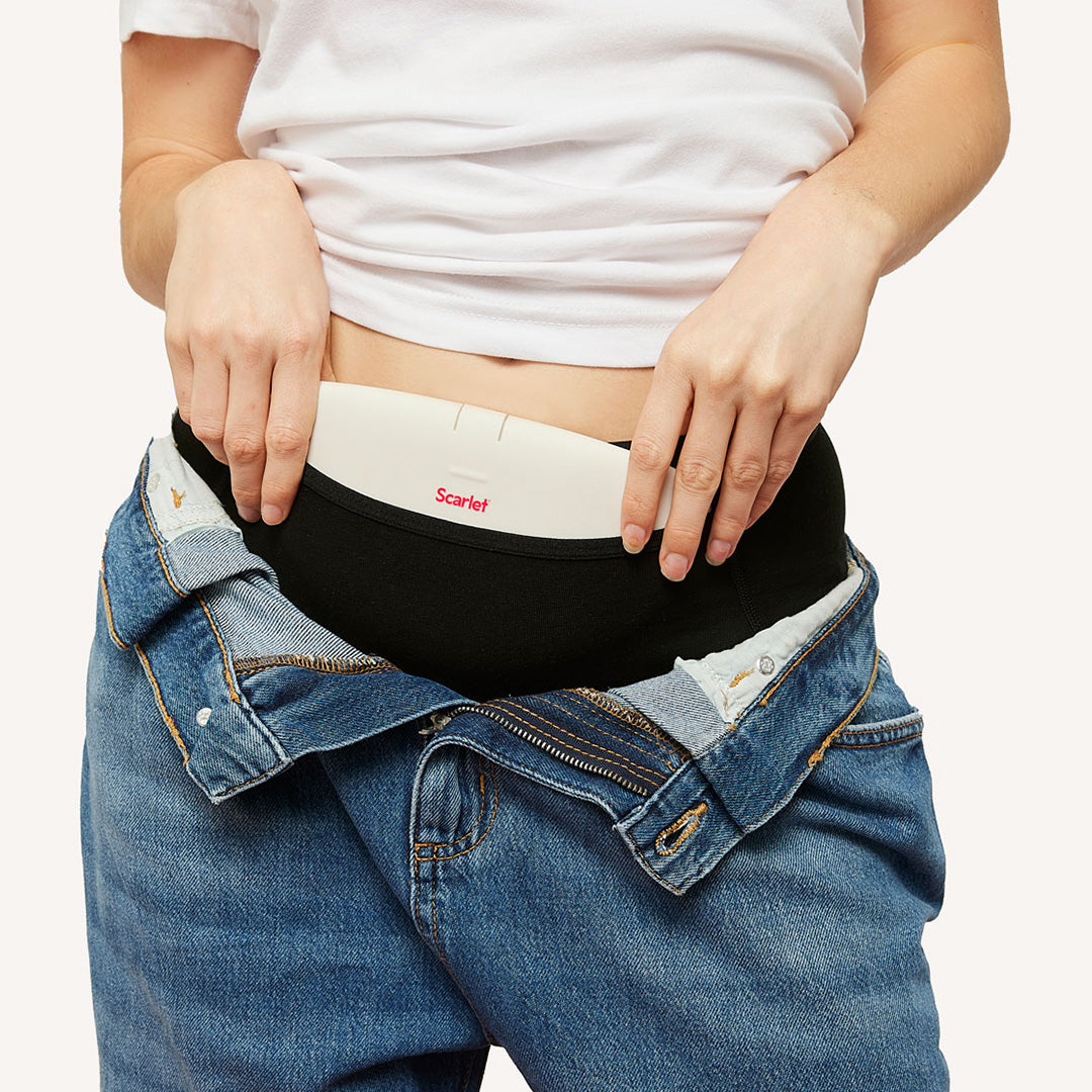 Hands tucking the white rae heat pad into black underwear under open jeans